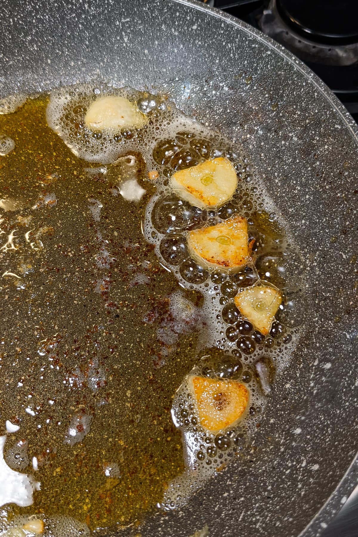 Fried garlic slices in melted butter in a sauce pan.
