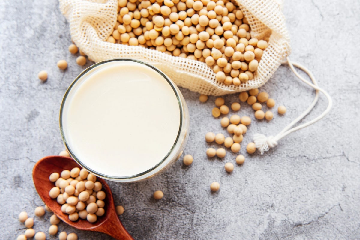 Top view of a glass with soy milk near some soy beans.
