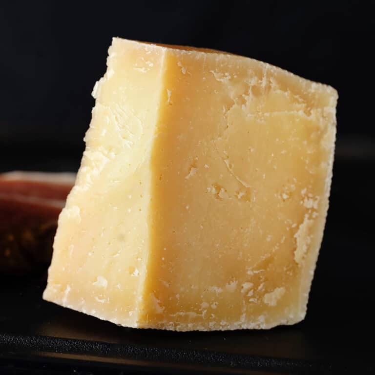 Close look of a parmesan wedge on a dark background.