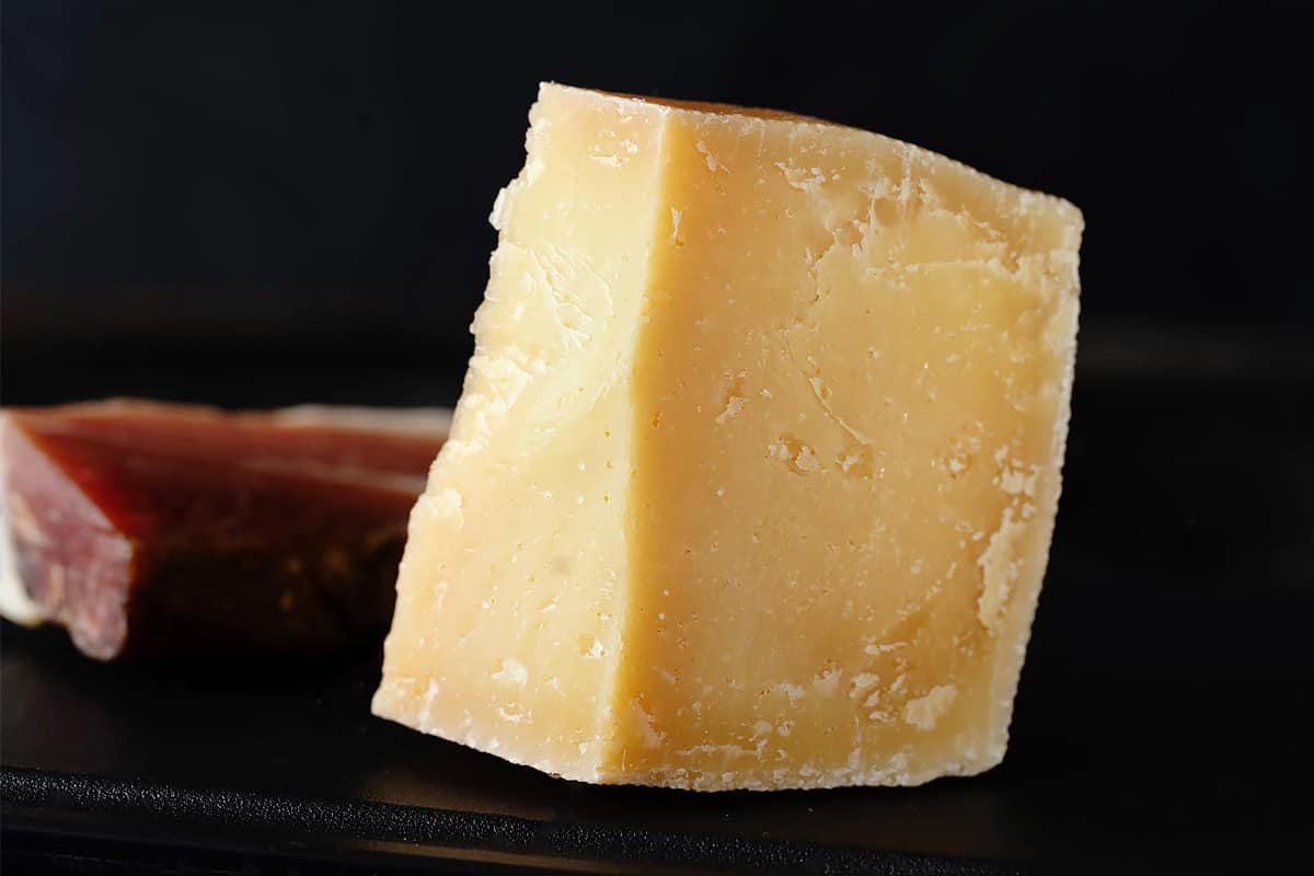 Close look of a parmesan piece on a black background.