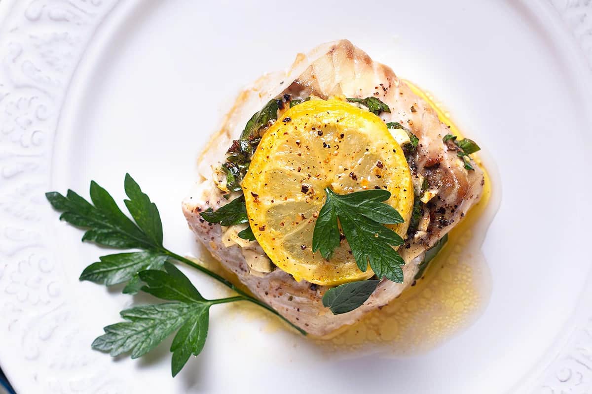 Top look of golden tile fish with a slice of lemon and parsley.
