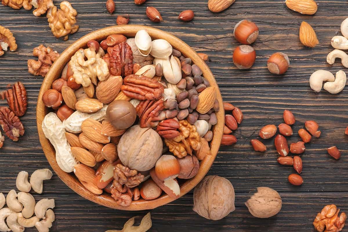 Top view of a plate with different nuts on a wooden table.