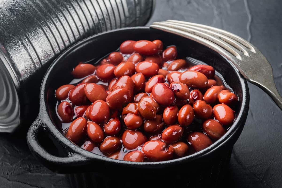 Close look of red beans with a can and fork on a dark background.