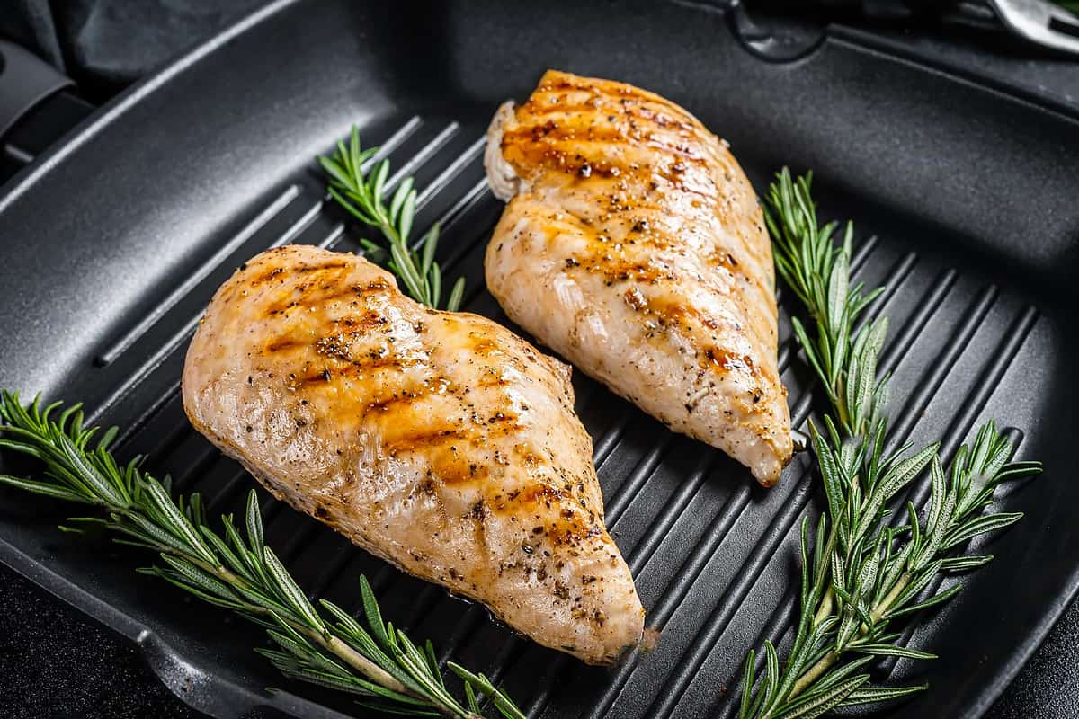 Close look of two chicken breasts grilled with rosemary bread.
