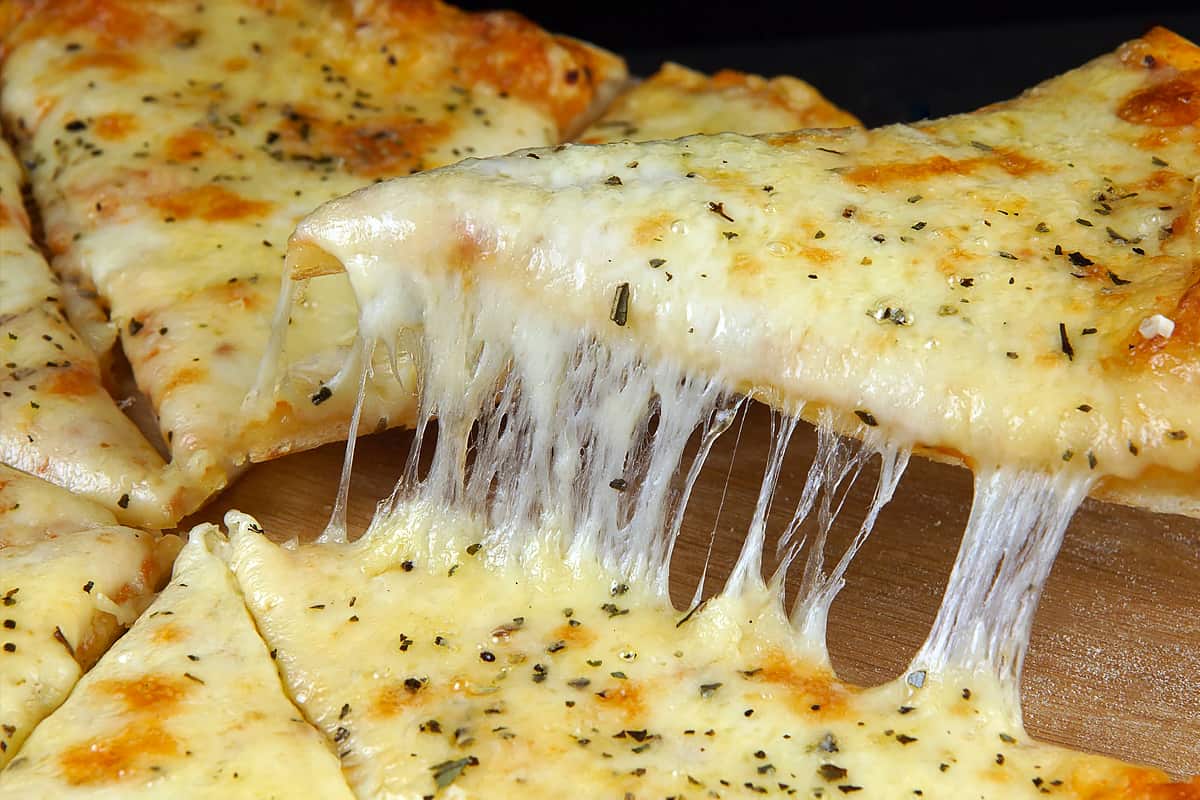 Melted cheese over a pizza slice.