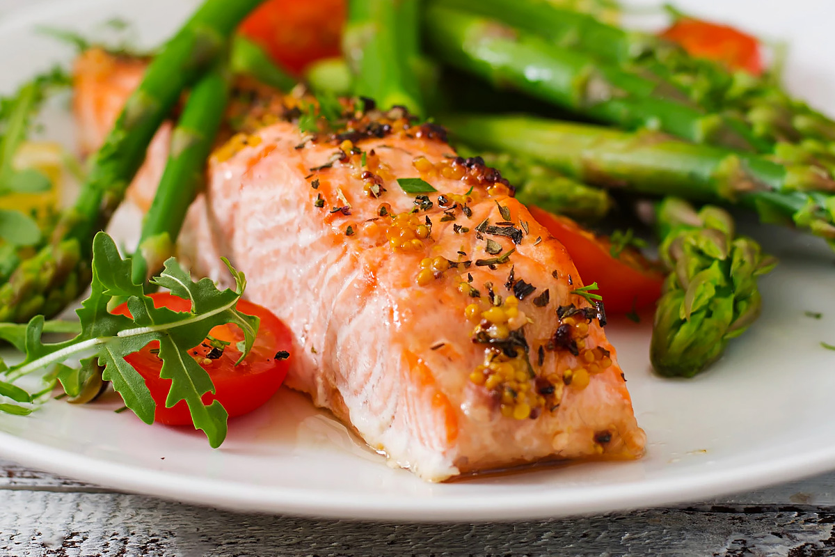 Close look of a cooked salmon with asparagus and tomatoes.