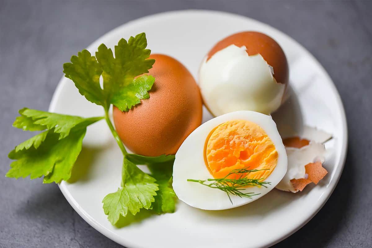 3 Boiled eggs in a plate with a parsley leaf.