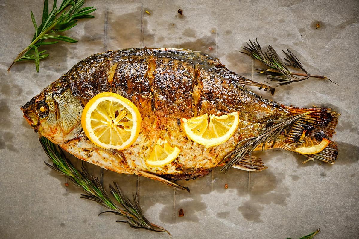 Baked fish with lemon slices on a parchment paper.
