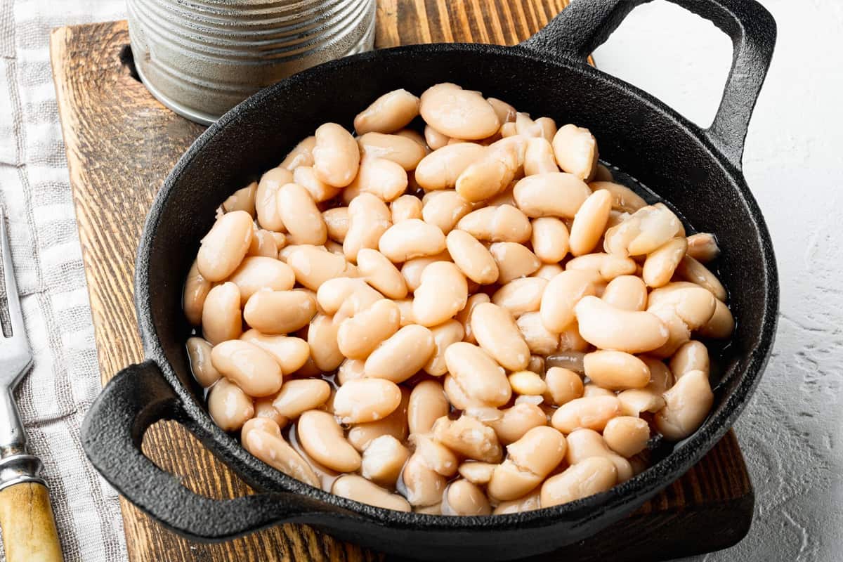 Close look of white beans from a can on a wooden board.