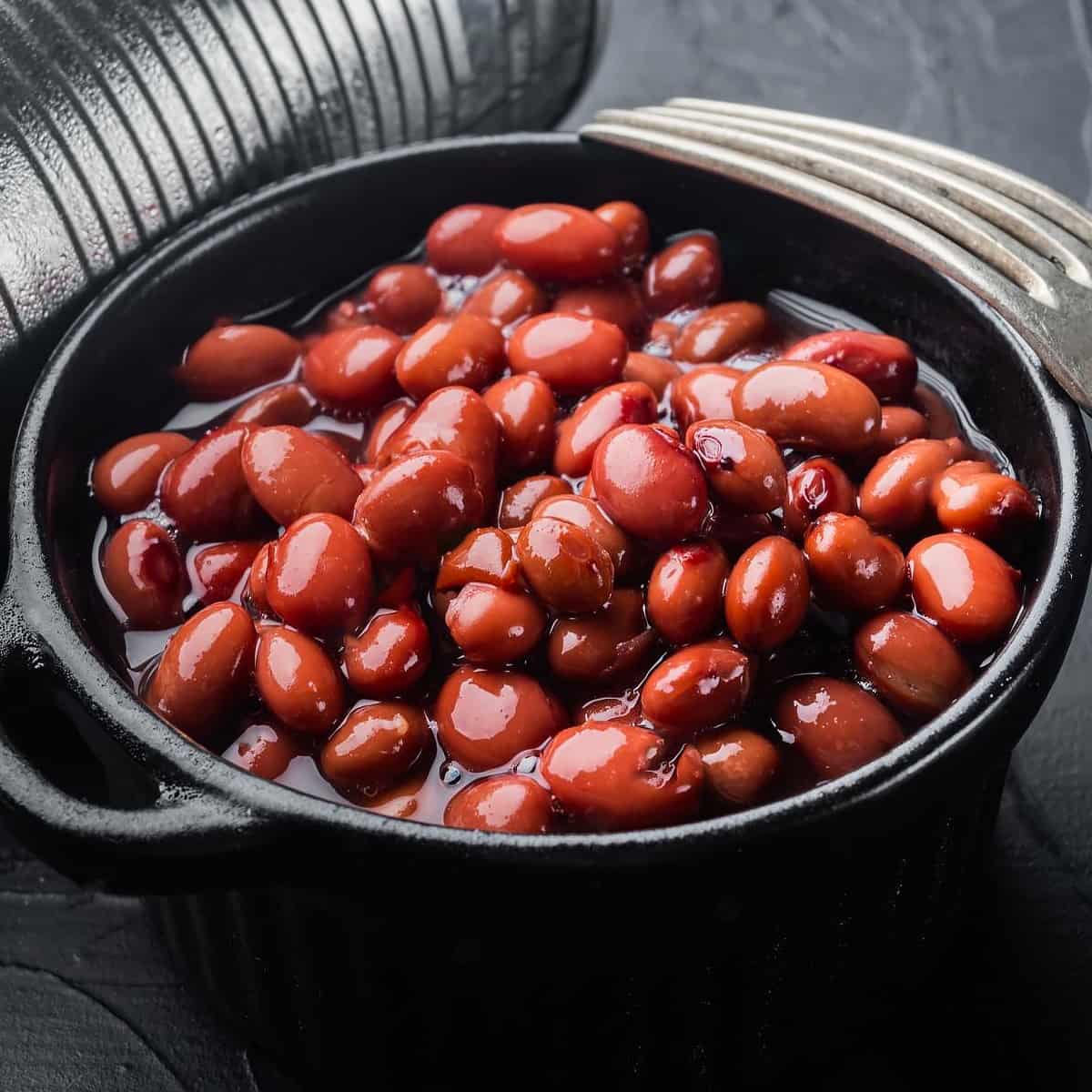 Red canned beans with fork on a dark background.