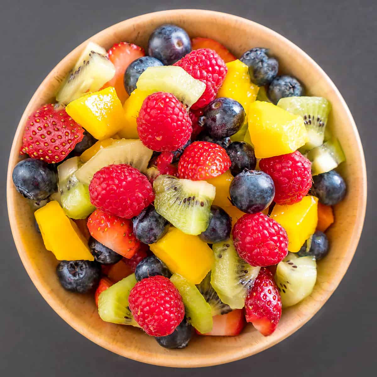 Top view of a bowl with strawberries, blueberries, kiwi, and mango.