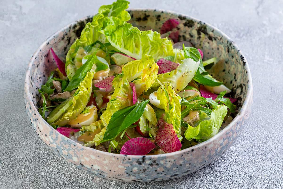 Close look of fresh green salad leaves in a concrete bowl.