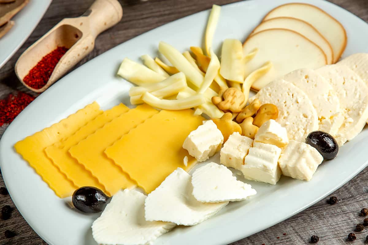 Different types of cheeses on a white plate.
