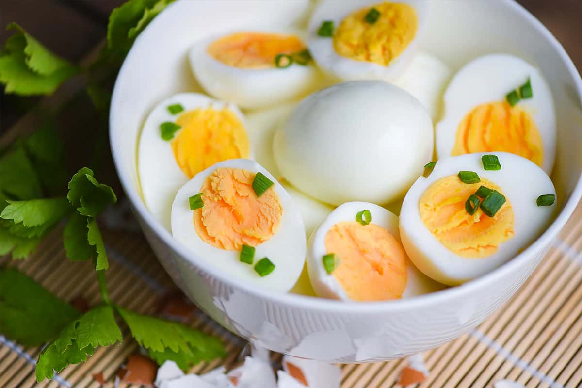White plate with halves of boiled eggs and sprinkled with green onions.