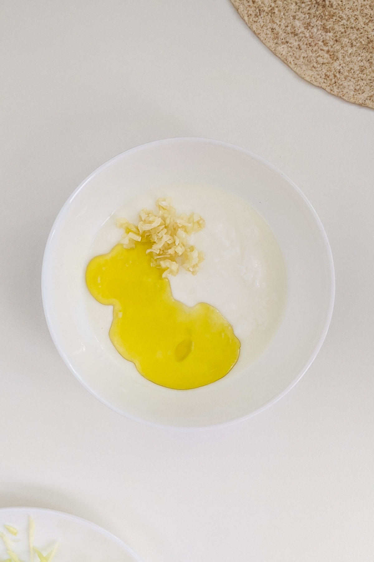Yogurt, oil and crushed garlic in a white plate.