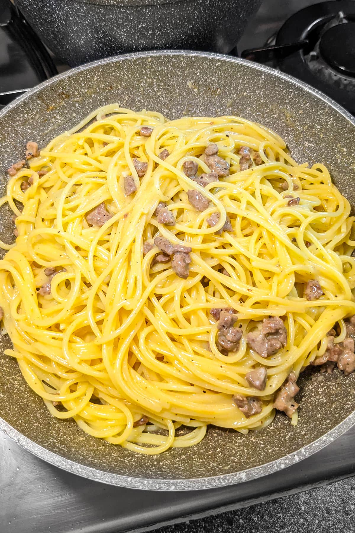 Beef carbonara in a sauce pan on the stove.