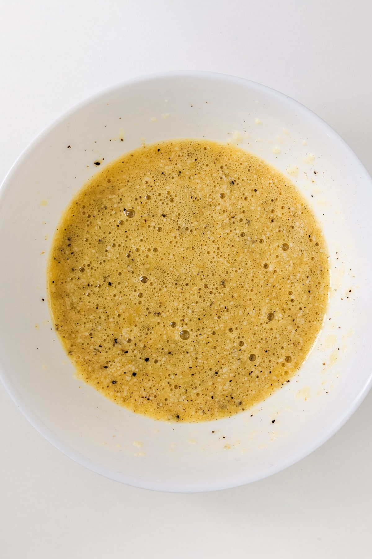 Top view of raw eggs mixed with parmesan cheese and black pepper.