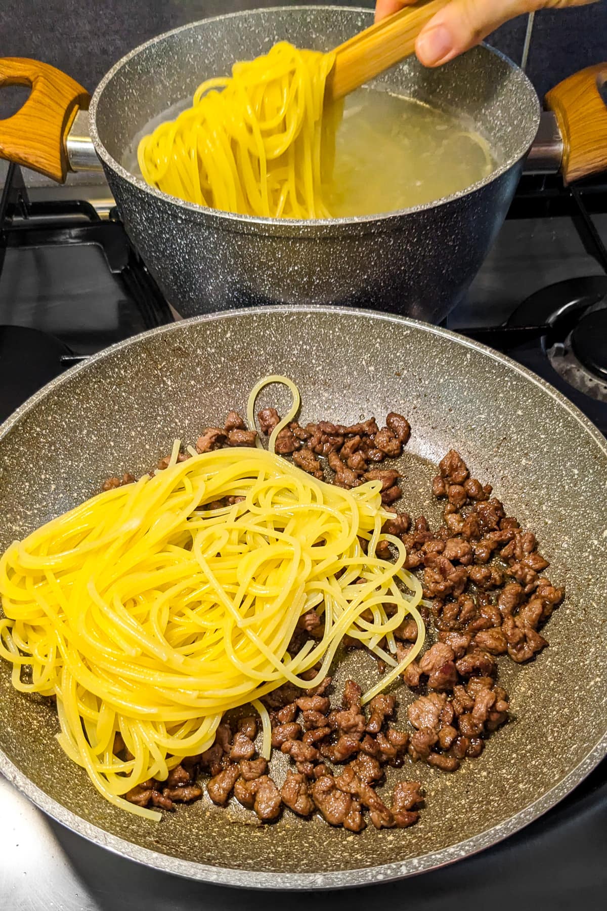 Sauce pan with spaghetti and fried ground beef.