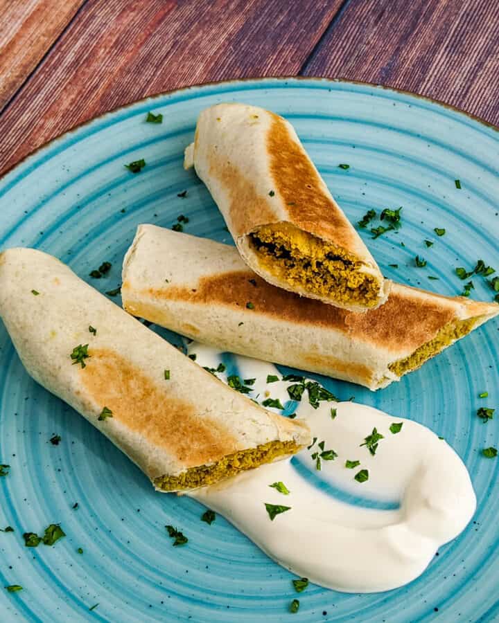 Close look of crispitos halves served with sour cream and chopped parsley.