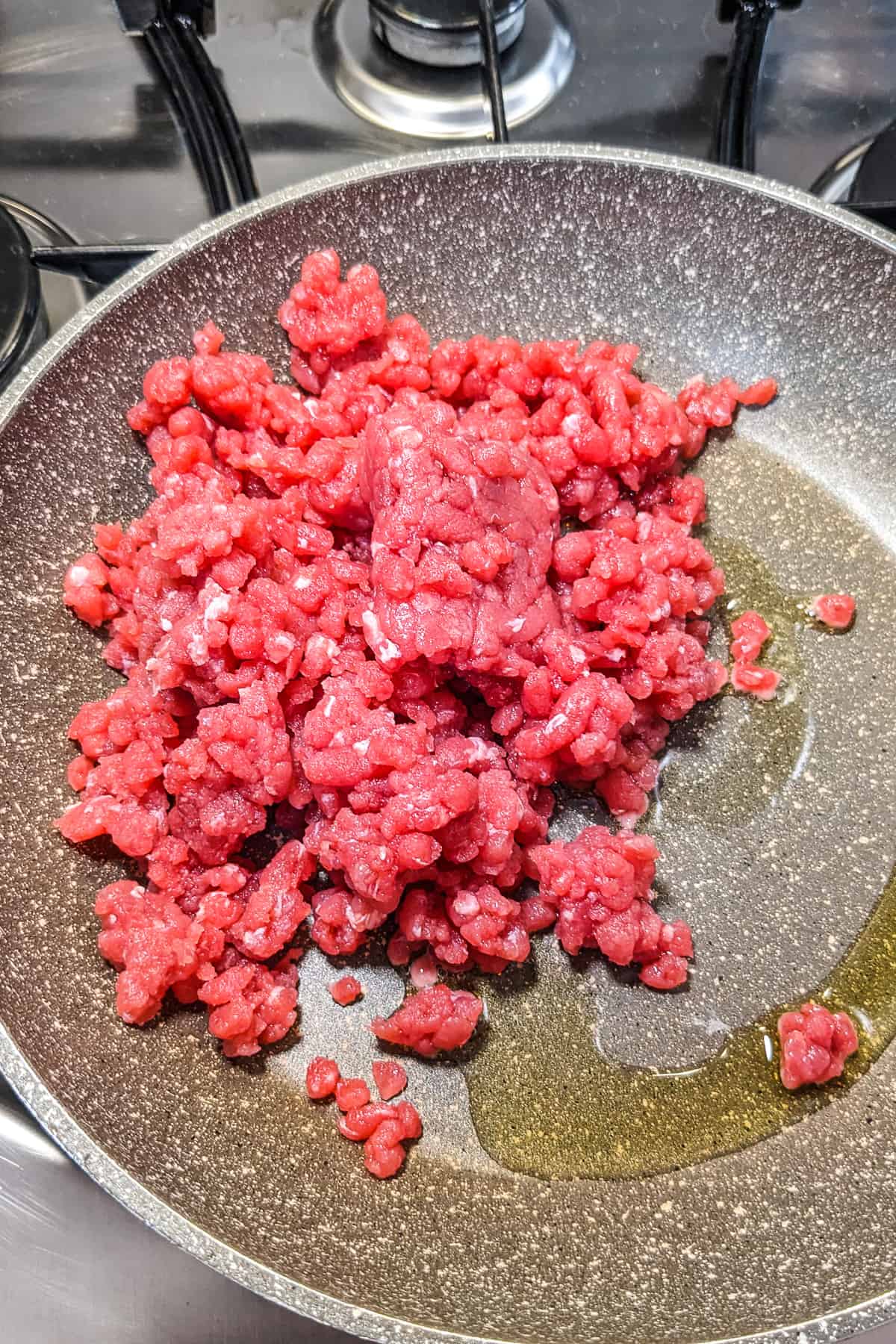 Close look of minced beef in a frying pan with a little bit of oil.