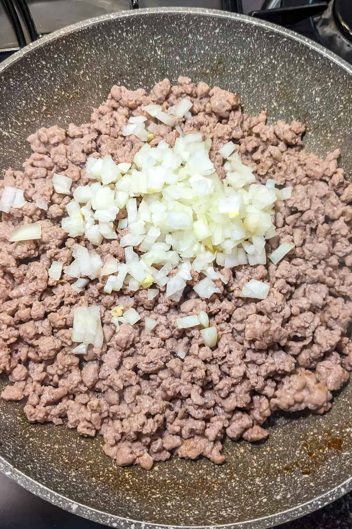 Fried minced beef with chopped onions in a frying pan.