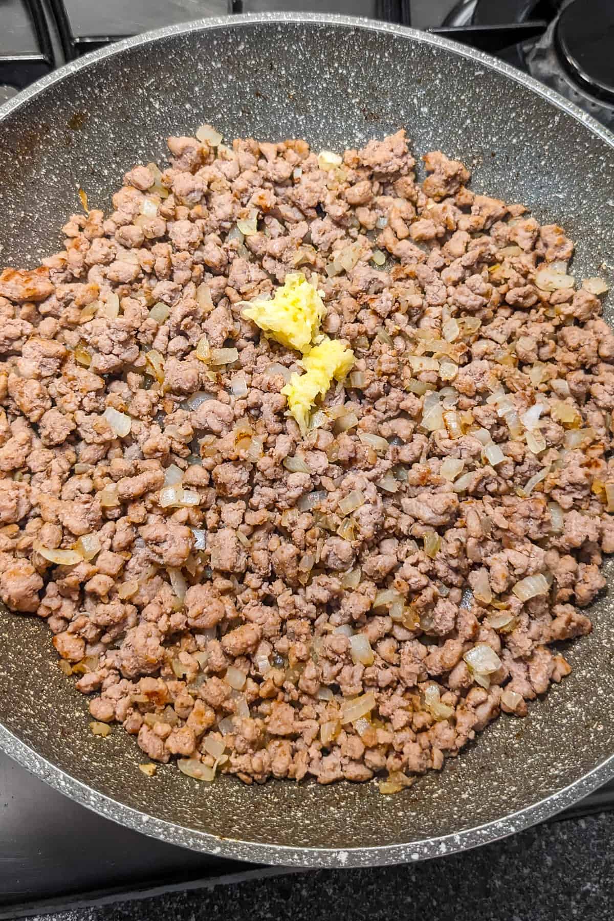 Fried minced beef with chopped garlic in a frying pan.
