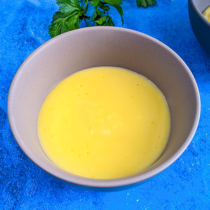 Egg yolk sauce in a plate on a blue table background.