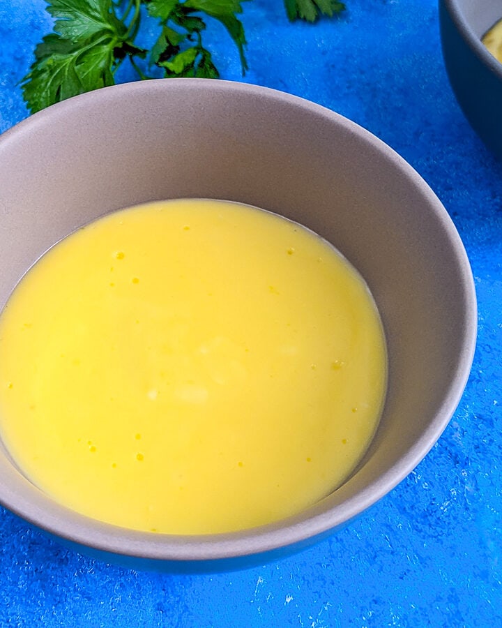 Egg yolk sauce in a plate on a blue table background.