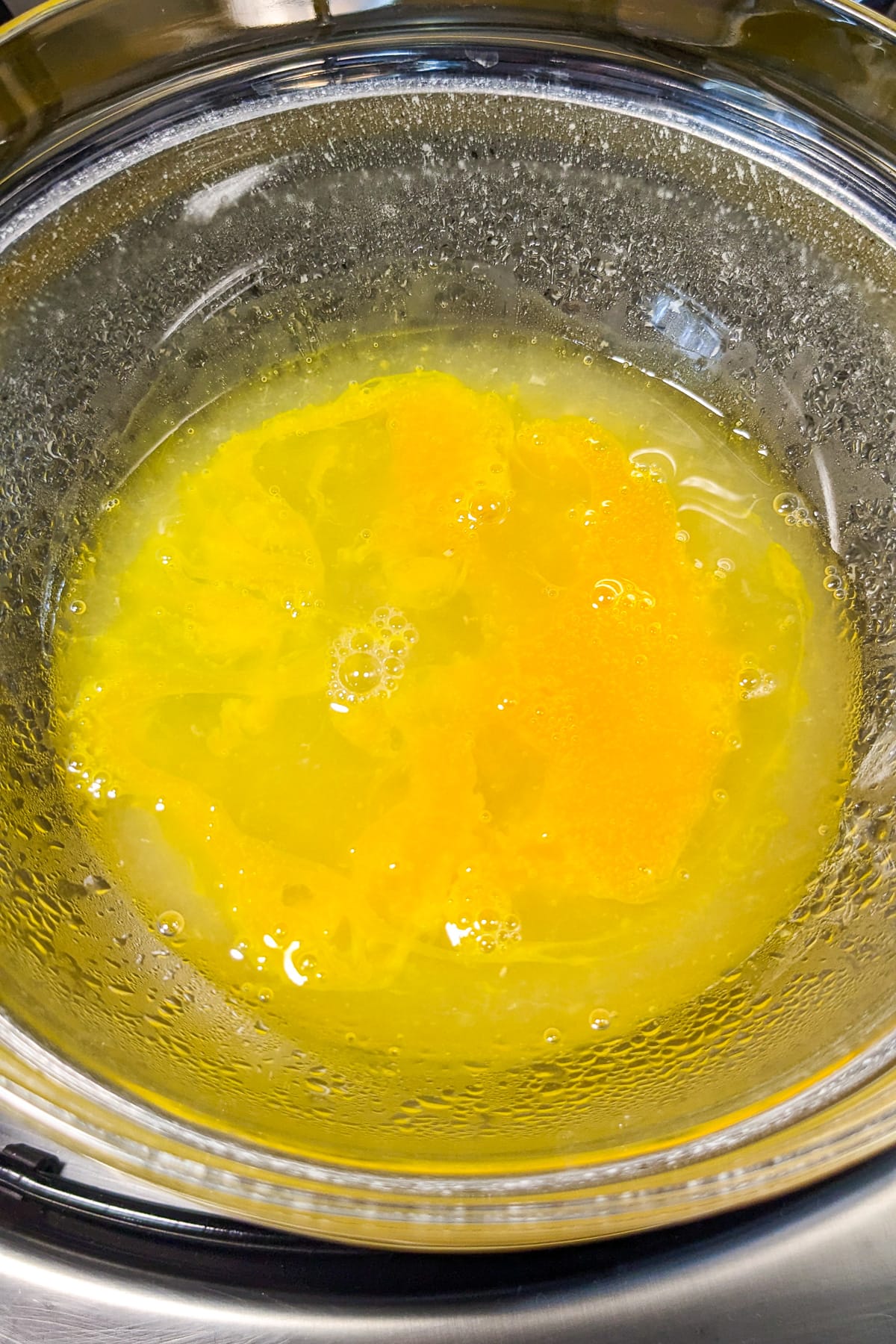 2 raw eggs mixed with lemon juice in a transparent bowl.