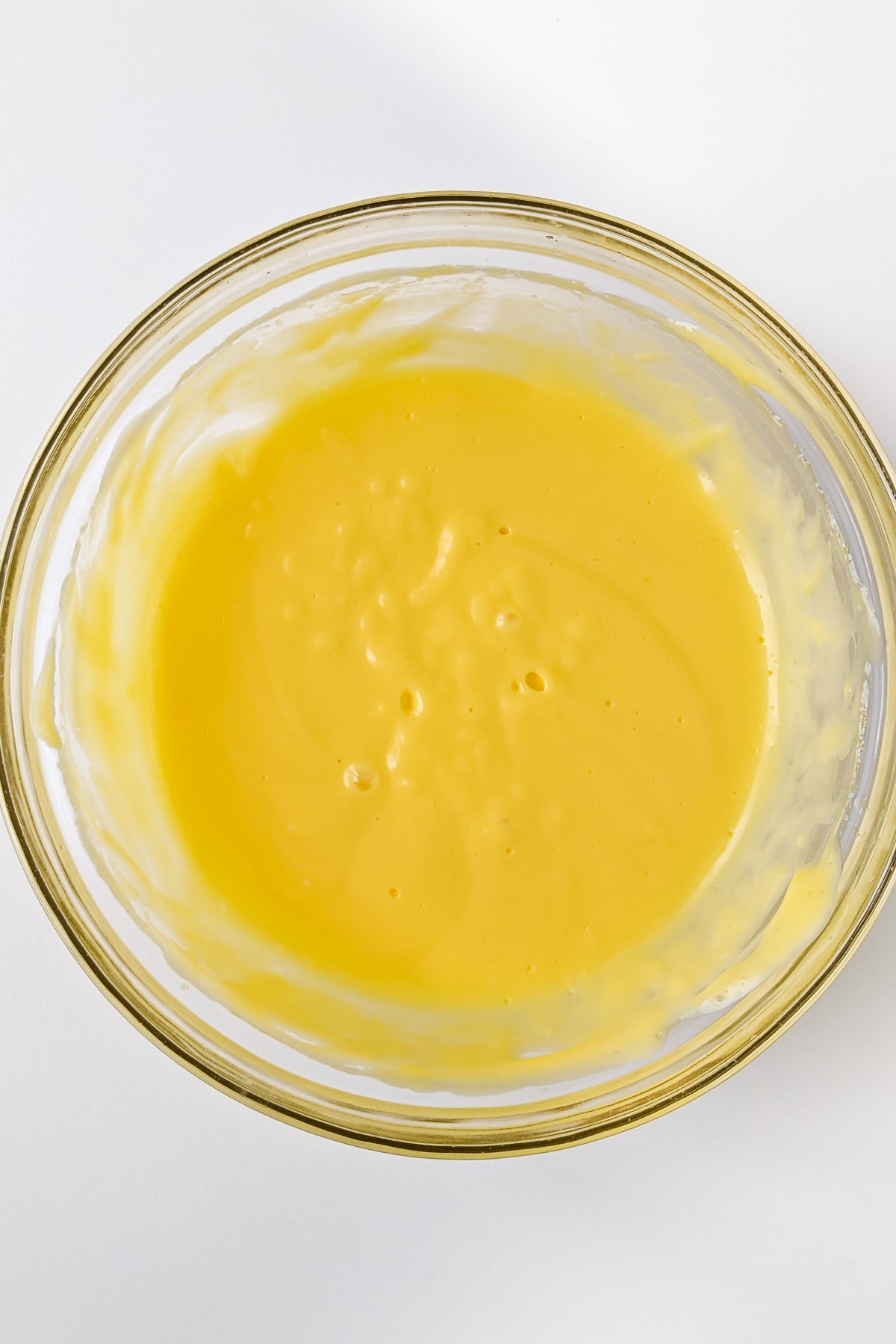 Mixed egg yolk sauce in a transparent bowl.
