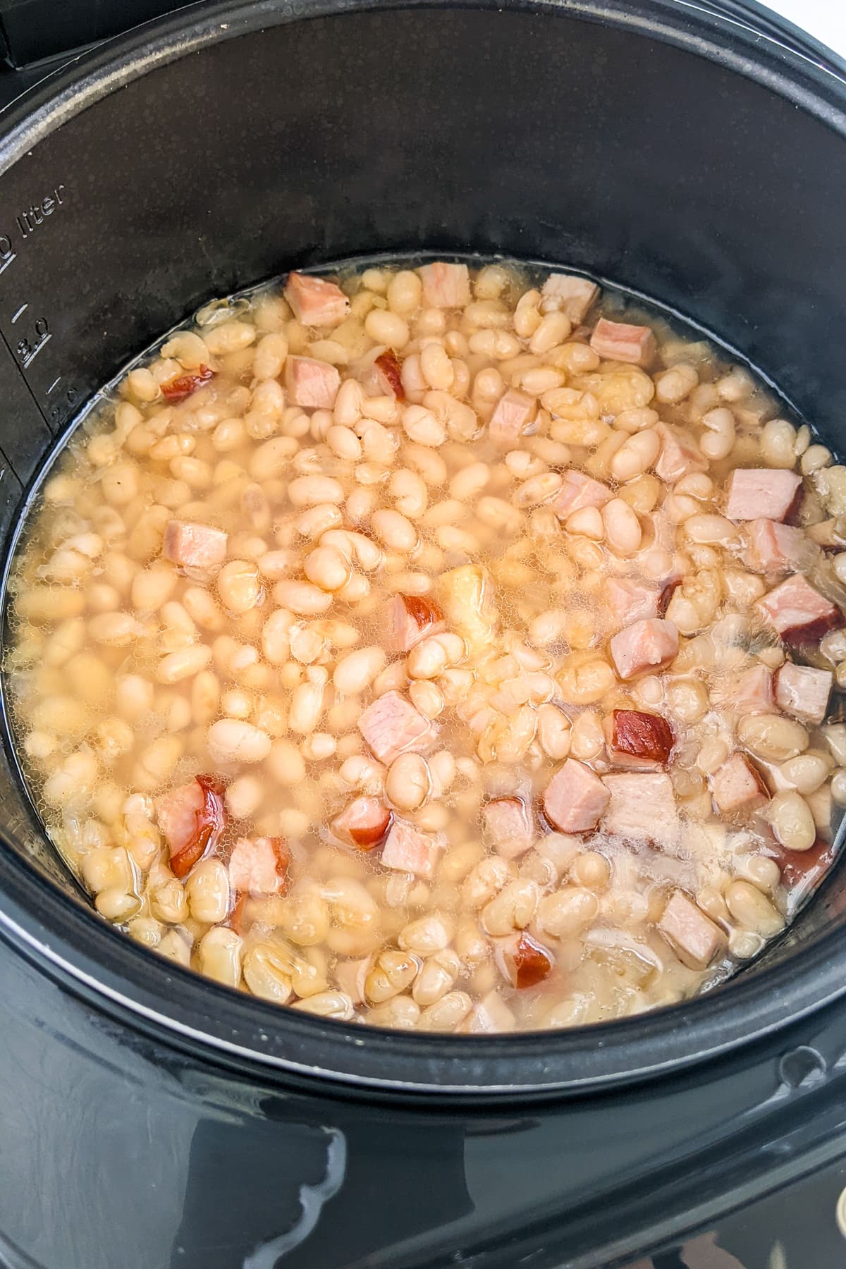 Cooked ham and beans stew in a slow cooker.
