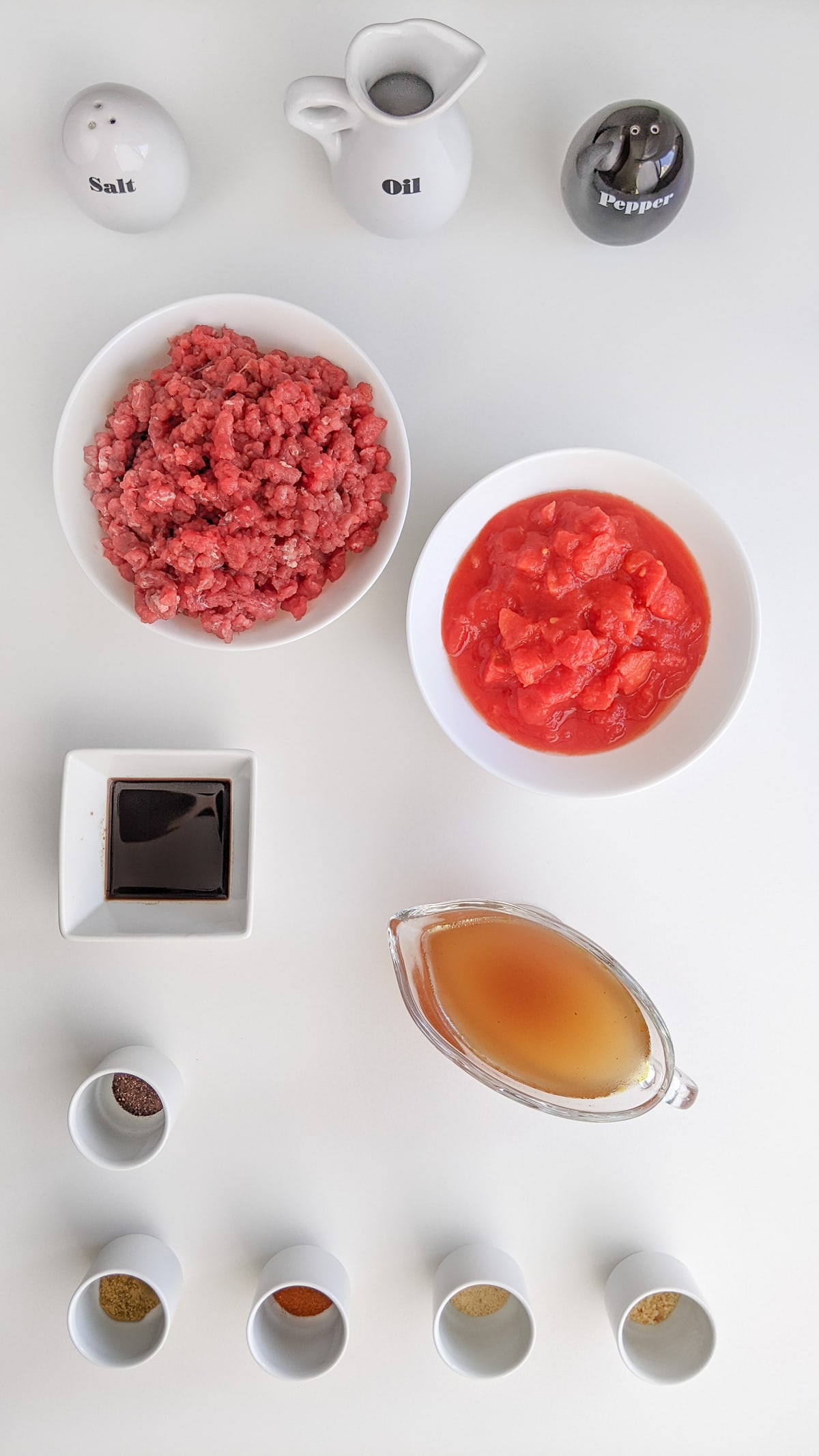 Ground beef with tomato sauce, spices and broth on a white table.