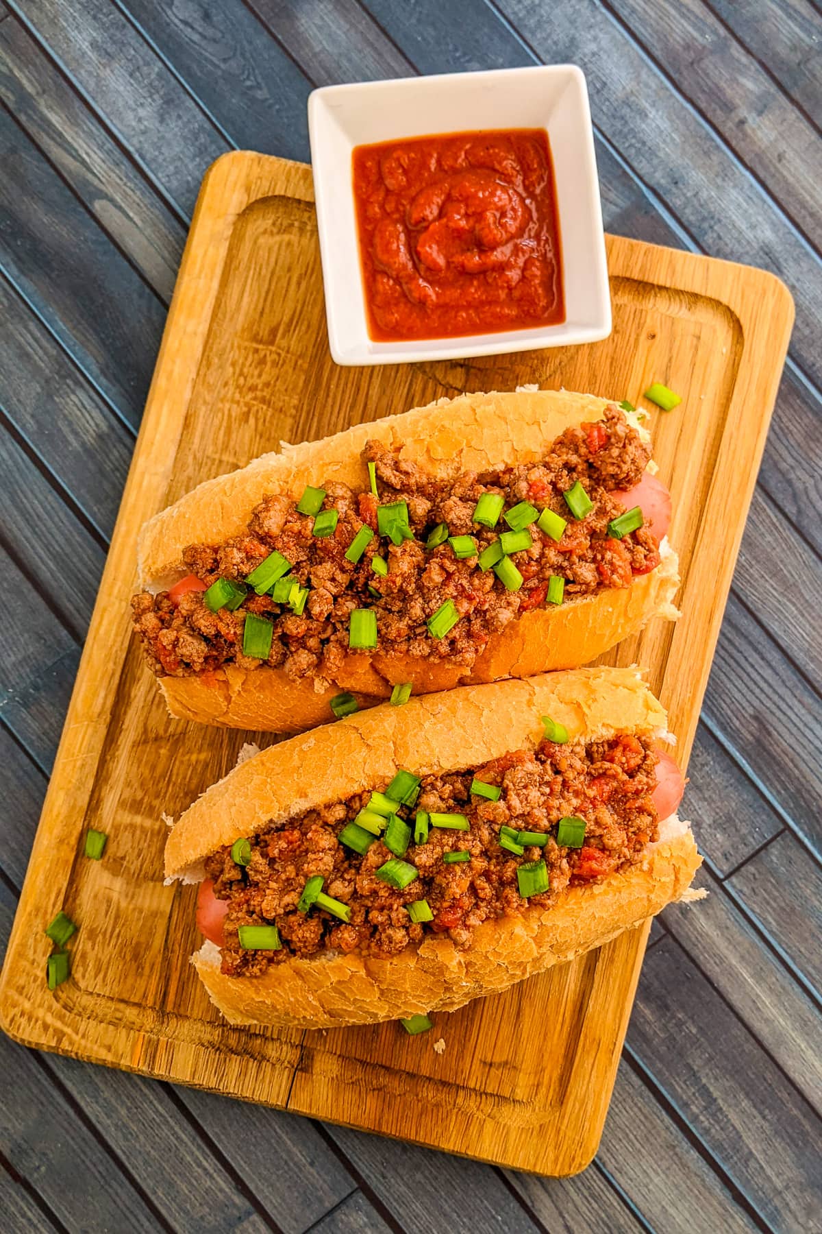 Top view of hot dog with chopped onions on a cutting board.