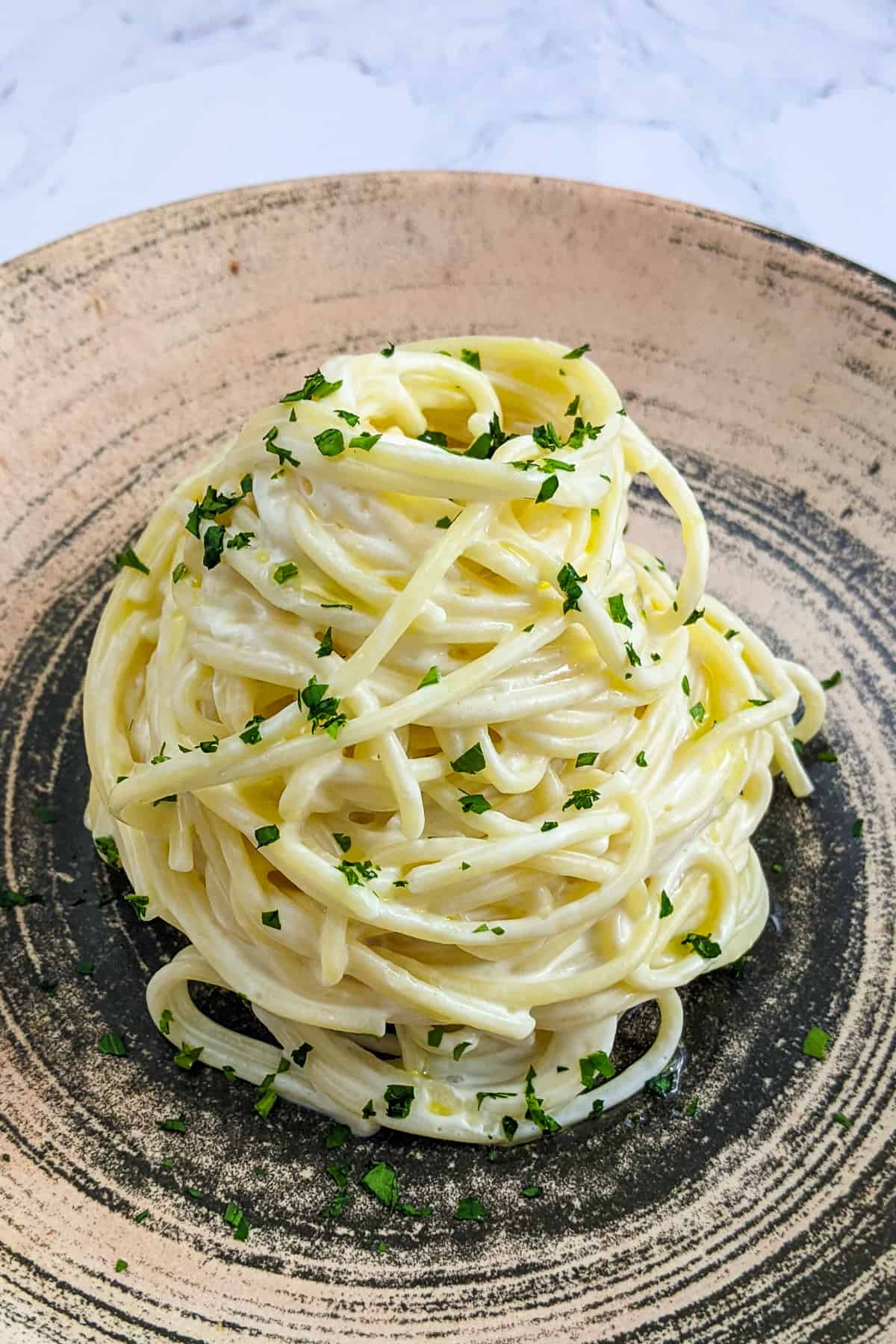 Restaurant style plate spaghetti with cream cheese and chopped parsley.