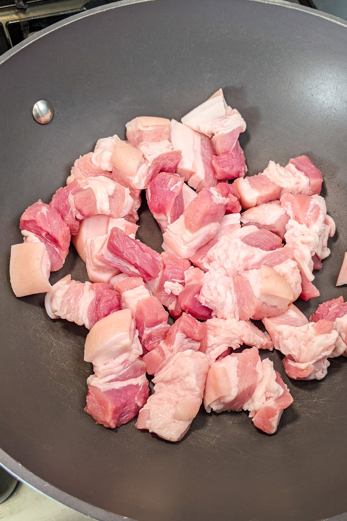 Raw pork belly in a wok.