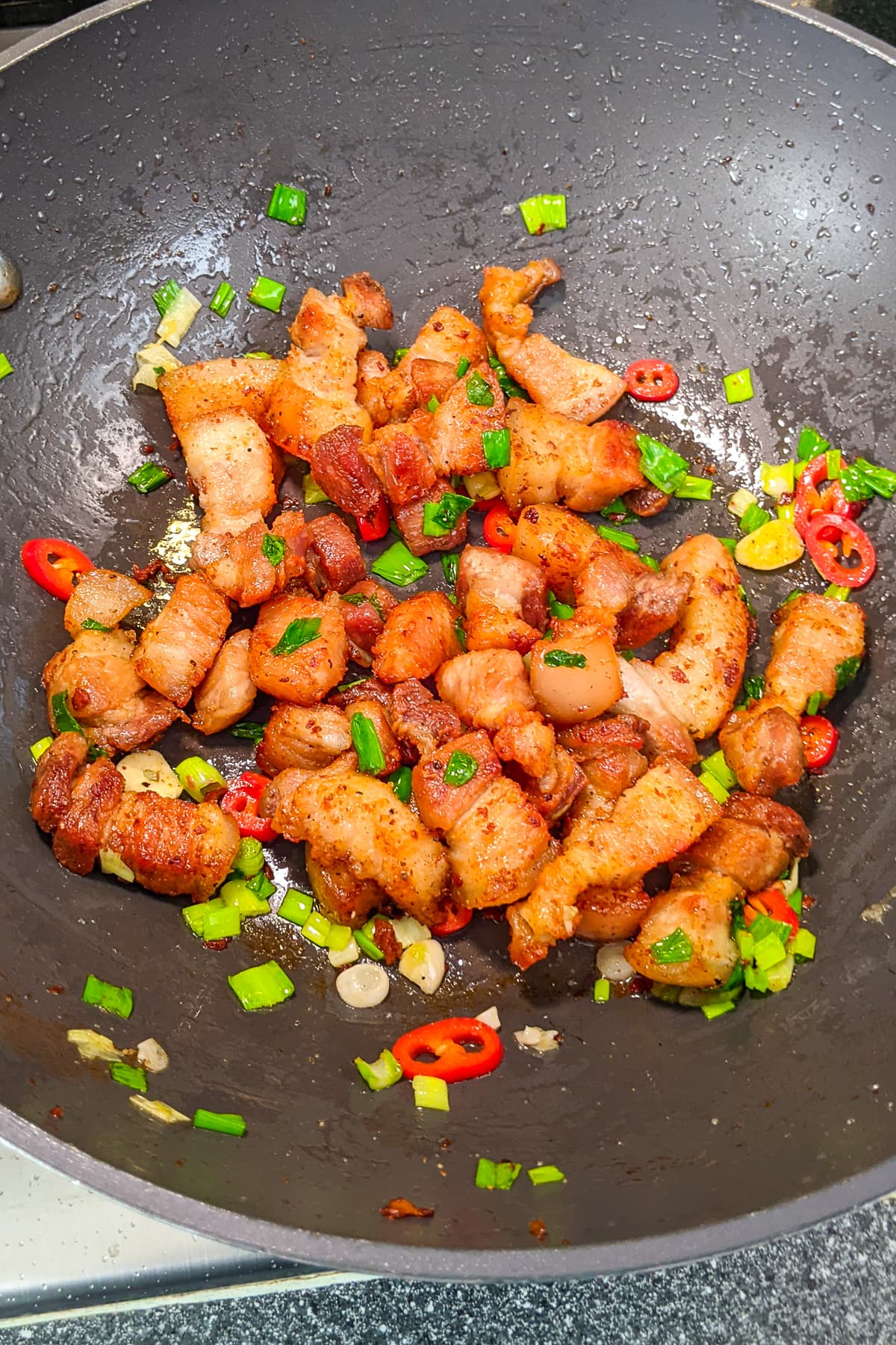 Frying pork belly with spring onions, chili pepper and garlic.