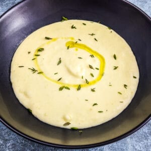 3 ingredient potato soup with olive oil, thyme in a black plate.