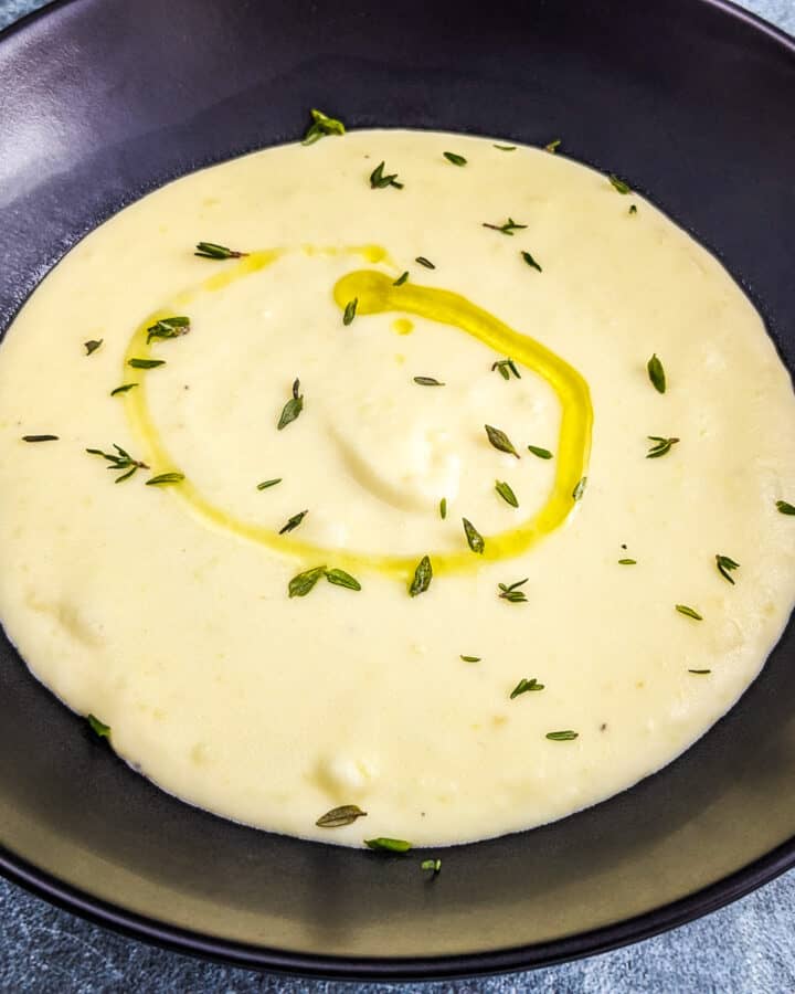 3 ingredient potato soup with olive oil, thyme in a black plate.