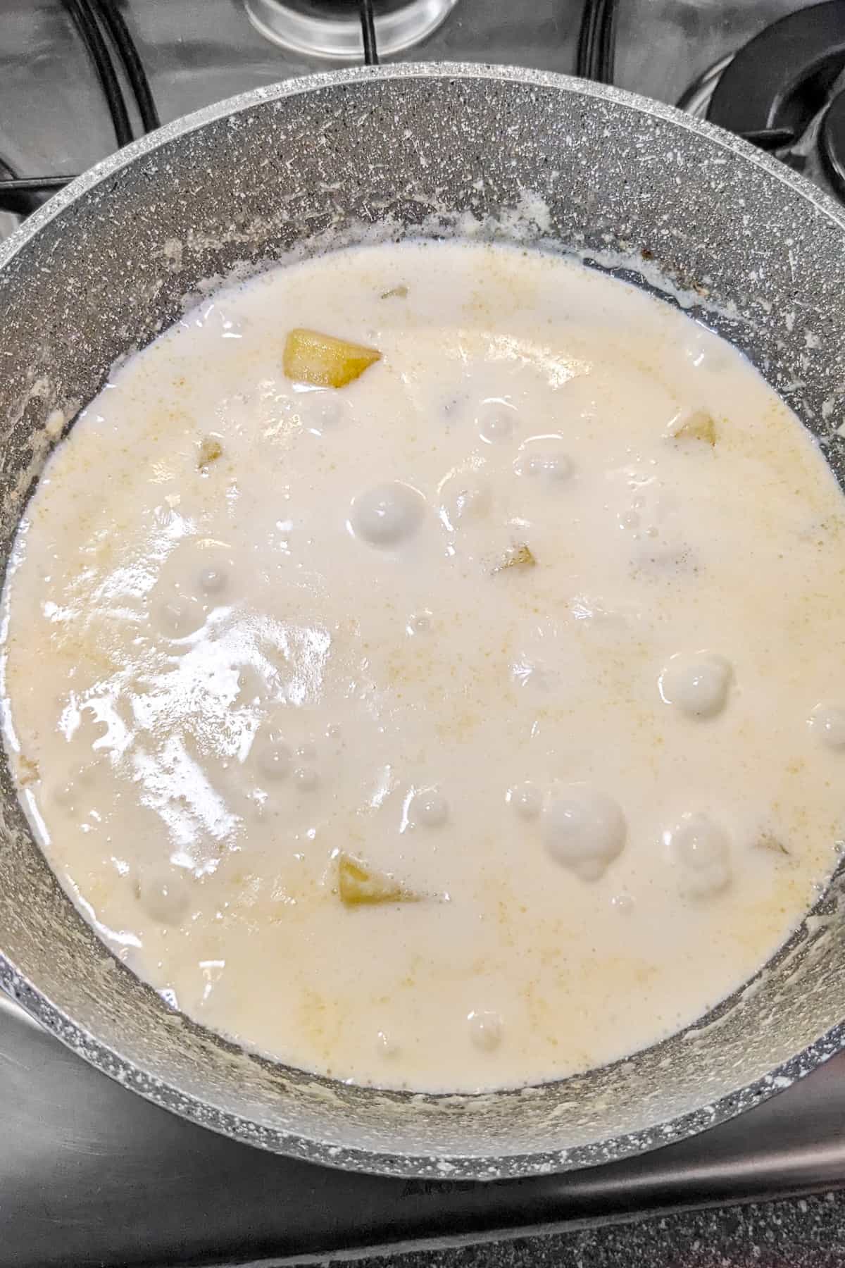 Potatoes with cream that are boiled on low heat on the stove.