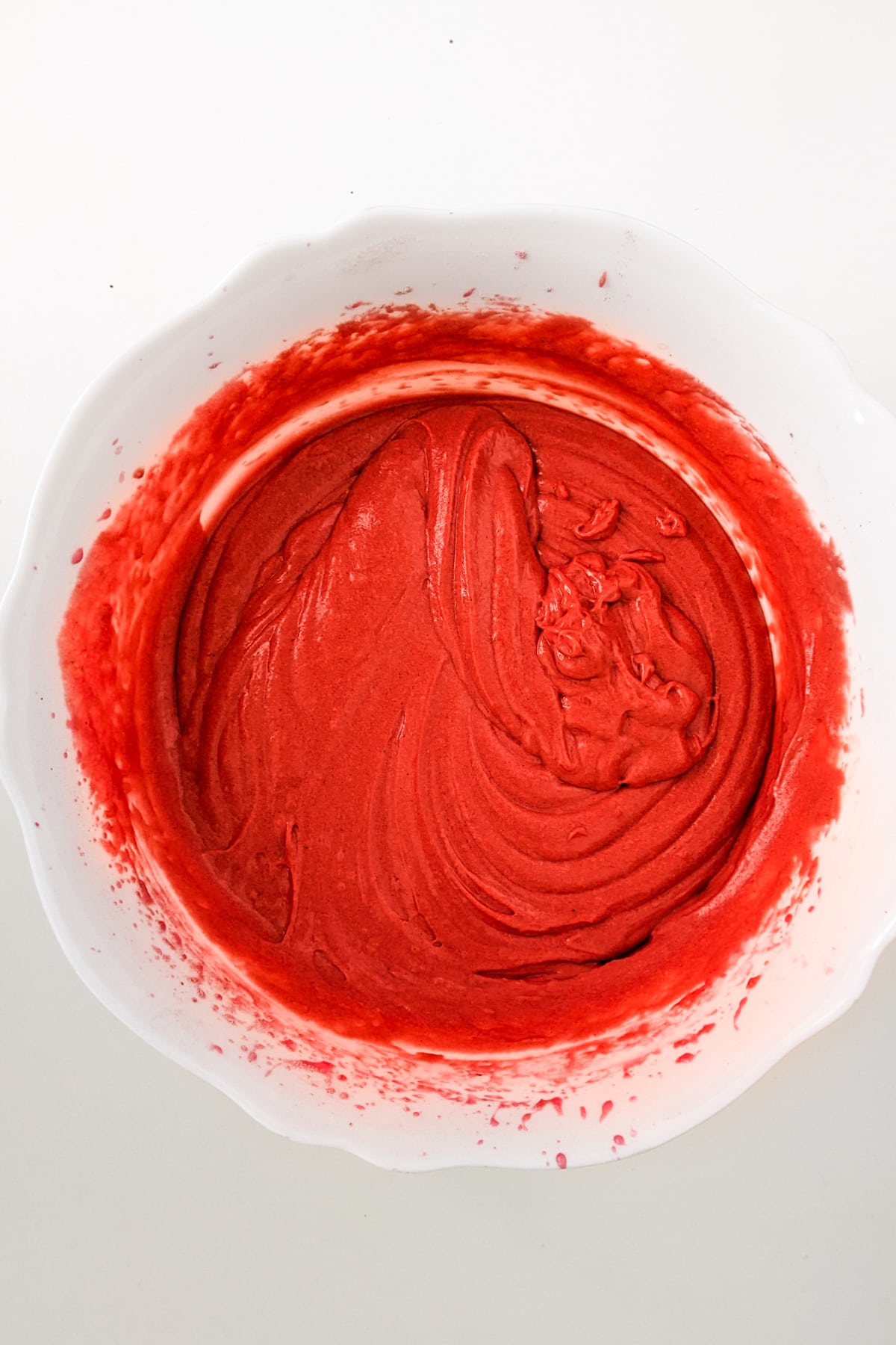 Top view of red cream mixed in a white bowl.