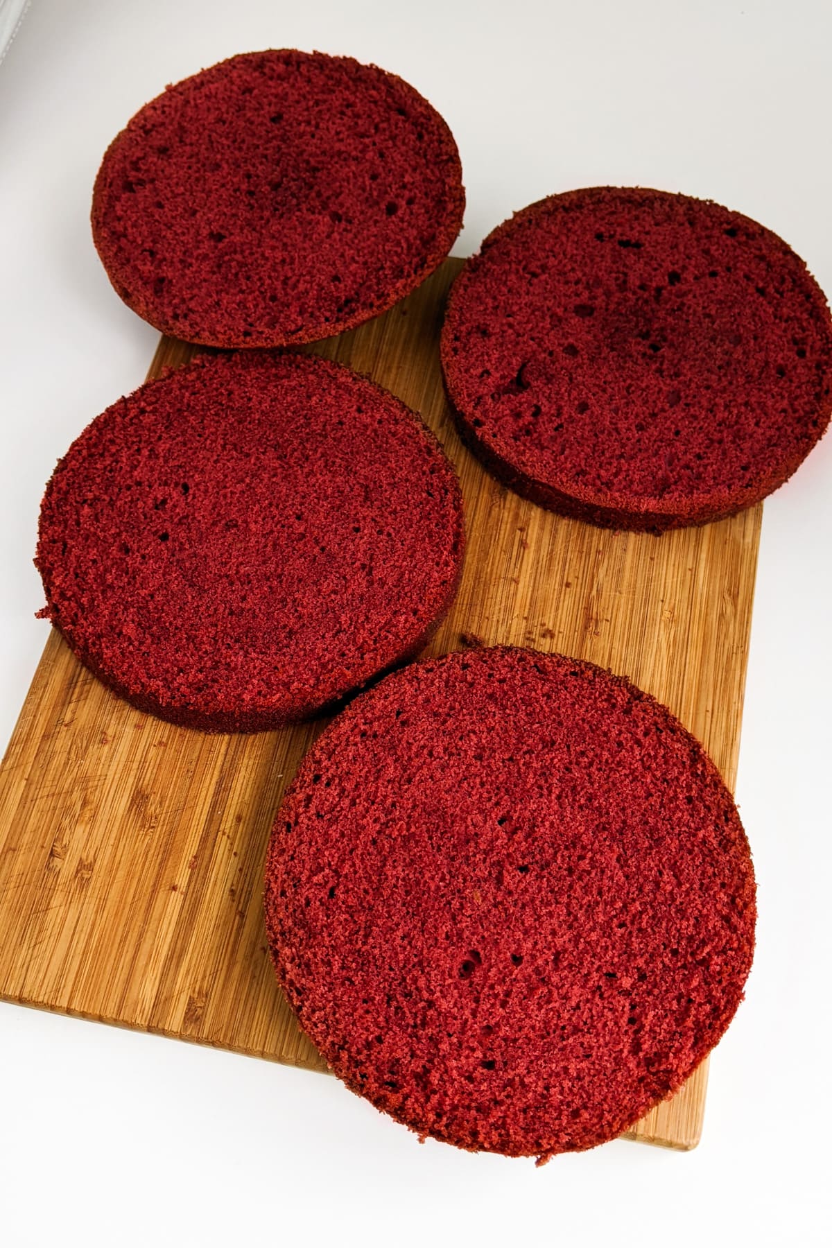 Red velvet cake sliced in 4 parts on a cutting board.