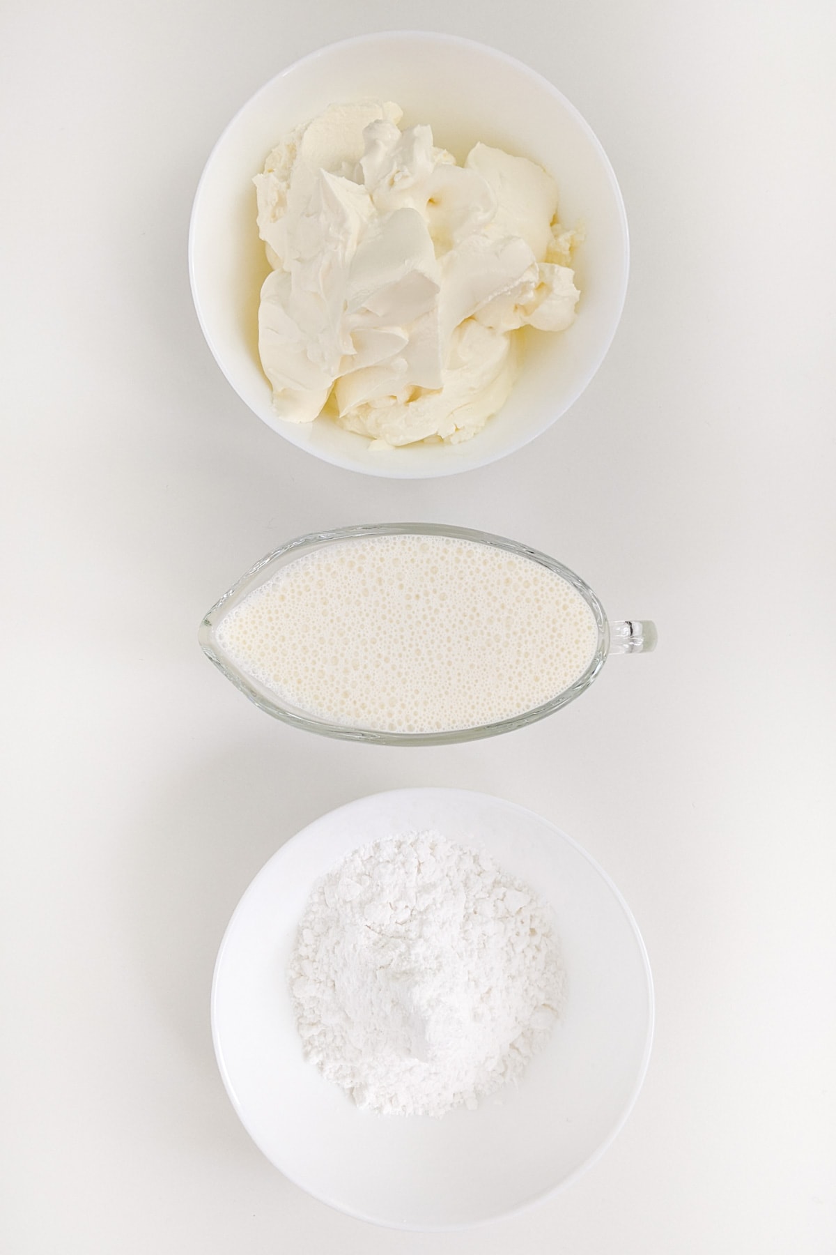 Cream cheese, near flour and cream on a white table.