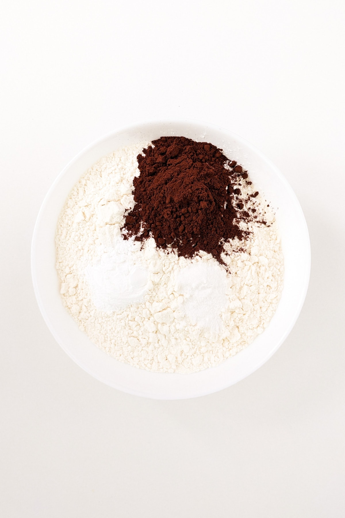 All purpose flour with natural cacao, and sugar in a white large bowl.