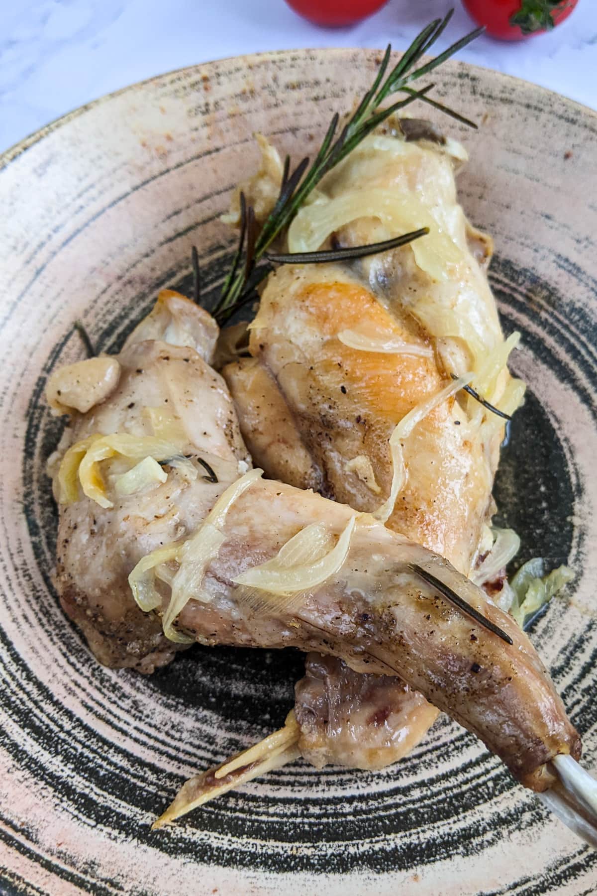 Juicy rabbit with rosemary and onions on a plate.