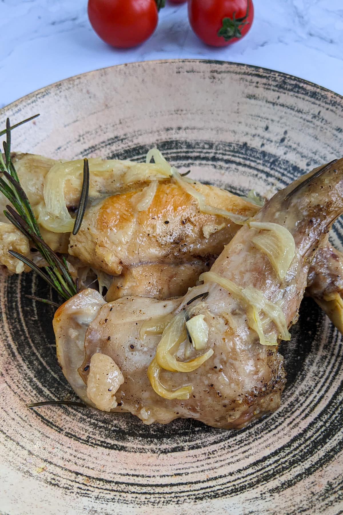 Close look of juicy rabbit meat with onions and rosemary.