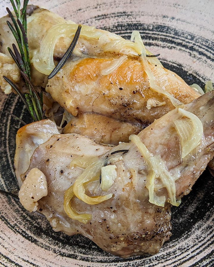 Close look of juicy rabbit meat with onions and rosemary.