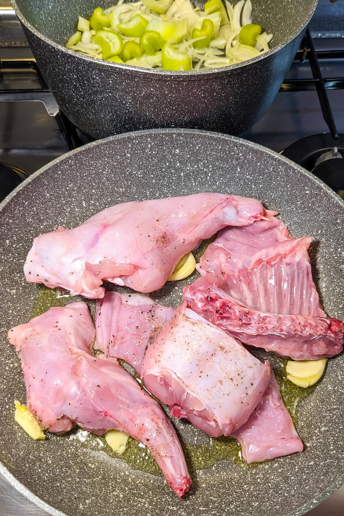 Frying rabbit meat in a garlicky olive oil on the stove.