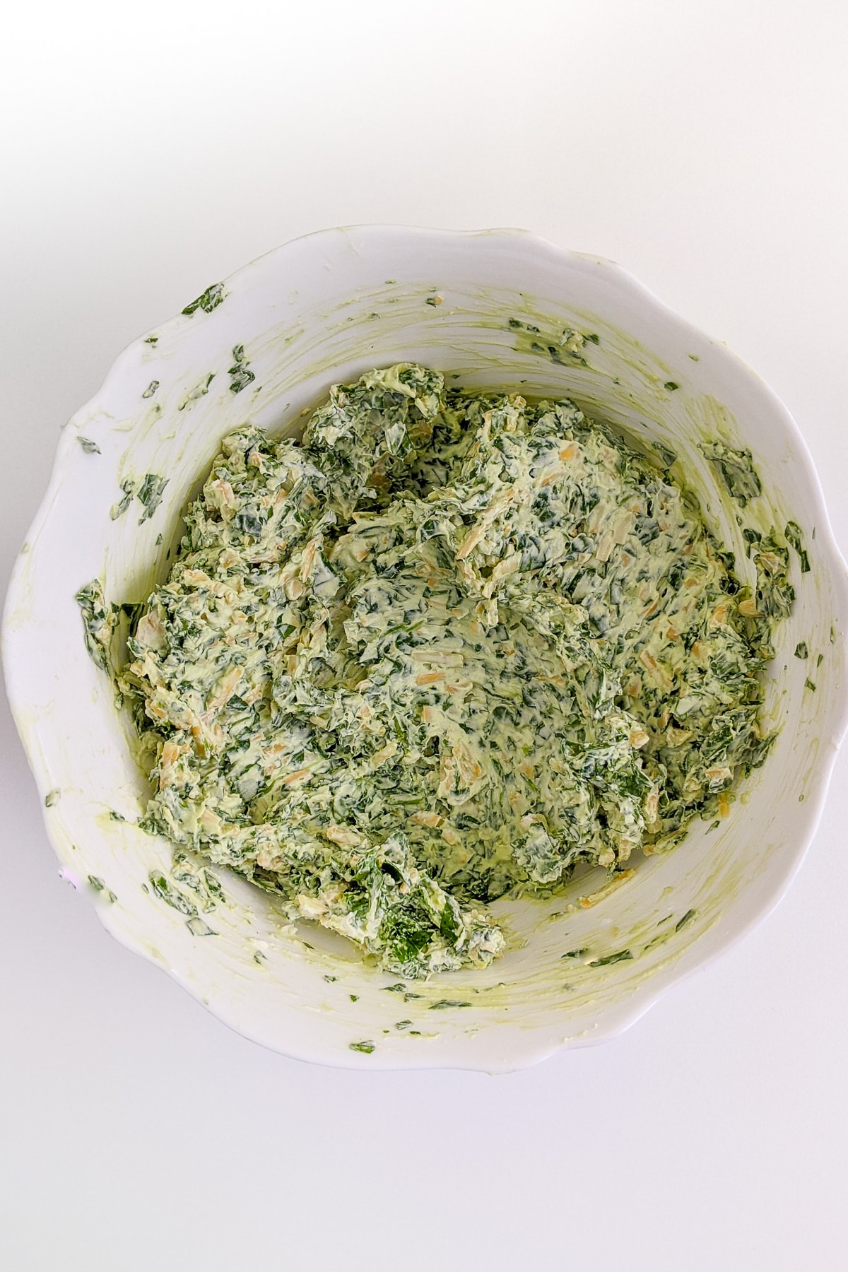 Top view of spinach dip mixture in a white plate.