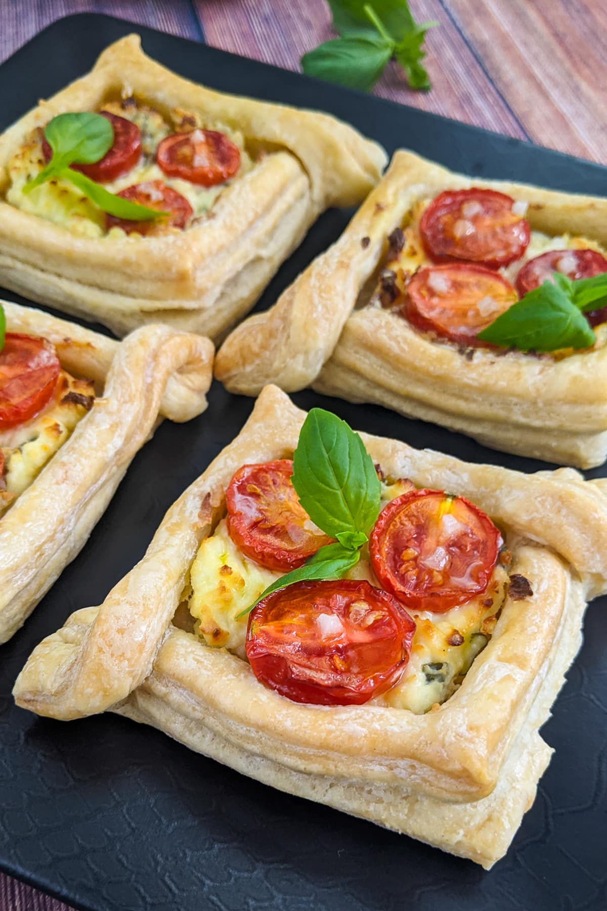 Close view of cherry tomato tartlets with cream cheese and basil.
