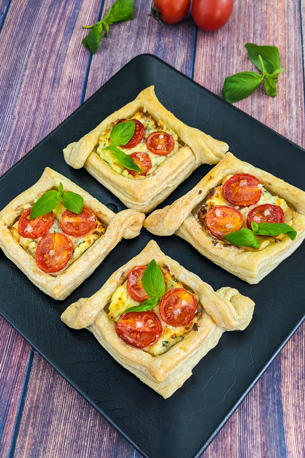 Close view of cherry tomato tartlets with cream cheese and basil.
